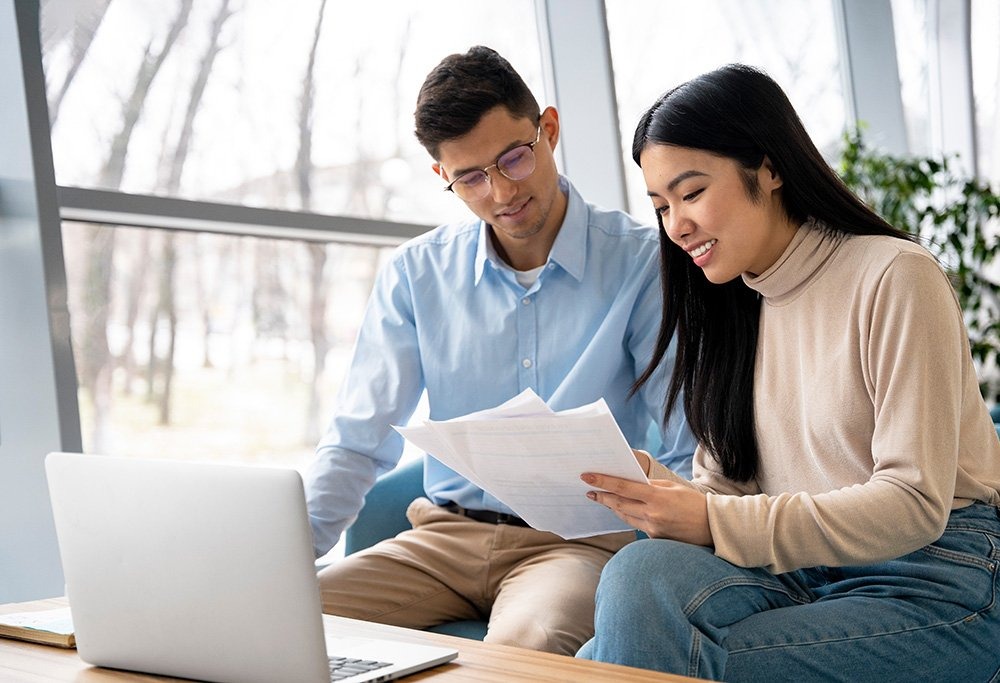 Two person working together. A woman showing some papers to a man